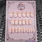 Peach nails with a white airbrush tip, bow and pearl accents in short round