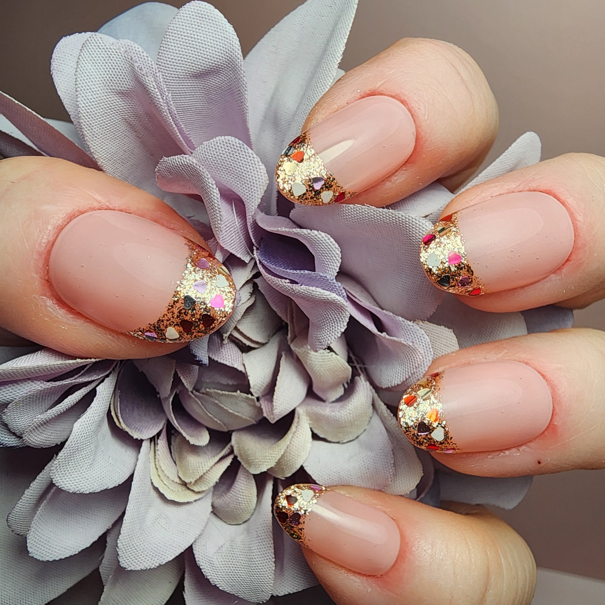 Soft nude press-on nails with confetti heart glitter French tips. Handmade luxury set with glossy finish—perfect for everyday, events, and bridal looks.